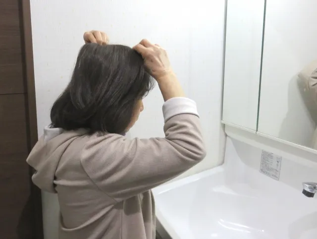 鏡の前でヘアピースを着けている女性